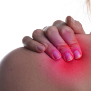 Strahlentherapiezentrum – Frau hält sich schmerzerfüllt die Schulter