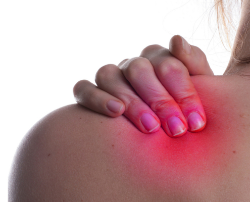 Strahlentherapiezentrum – Frau hält sich schmerzerfüllt die Schulter